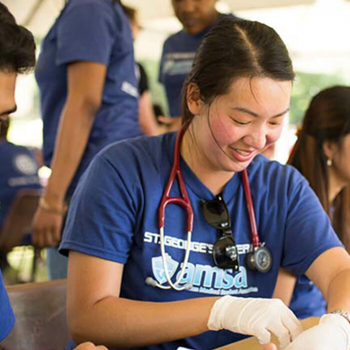 A small group of SGU students volunteer their time conducting physical exams during an outdoor clinic.