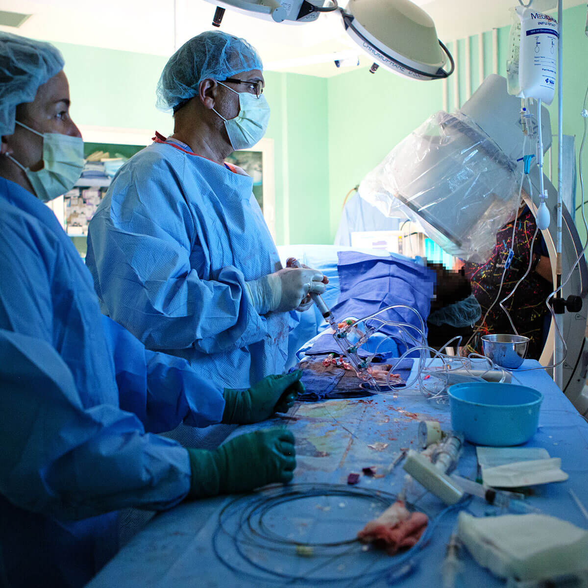 An interventional cardiologist performs a heart procedure while surrounded by other physicians and staff.