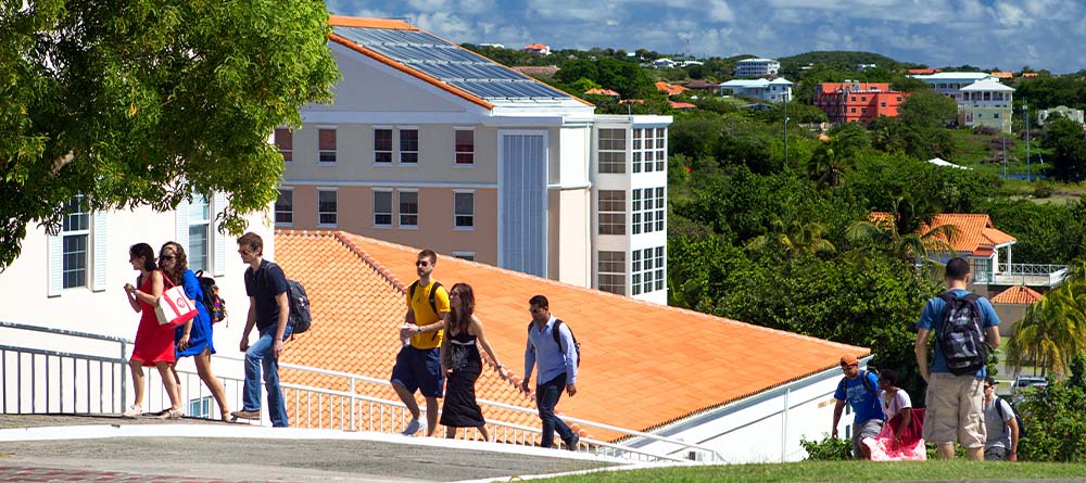 Students walking around SGU campus on sunny day.