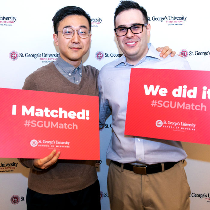 Two SGU students hold signs indicating they matched for residency at a Match Day celebration.