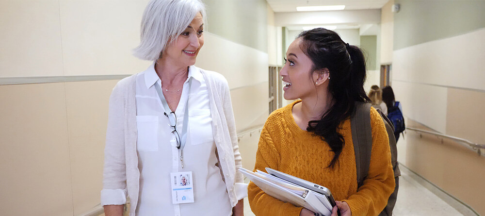 Pre-med student speaking with faculty mentor in hallway