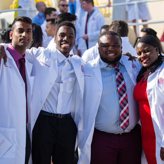 A group of SGU students gathers after receiving their white coats