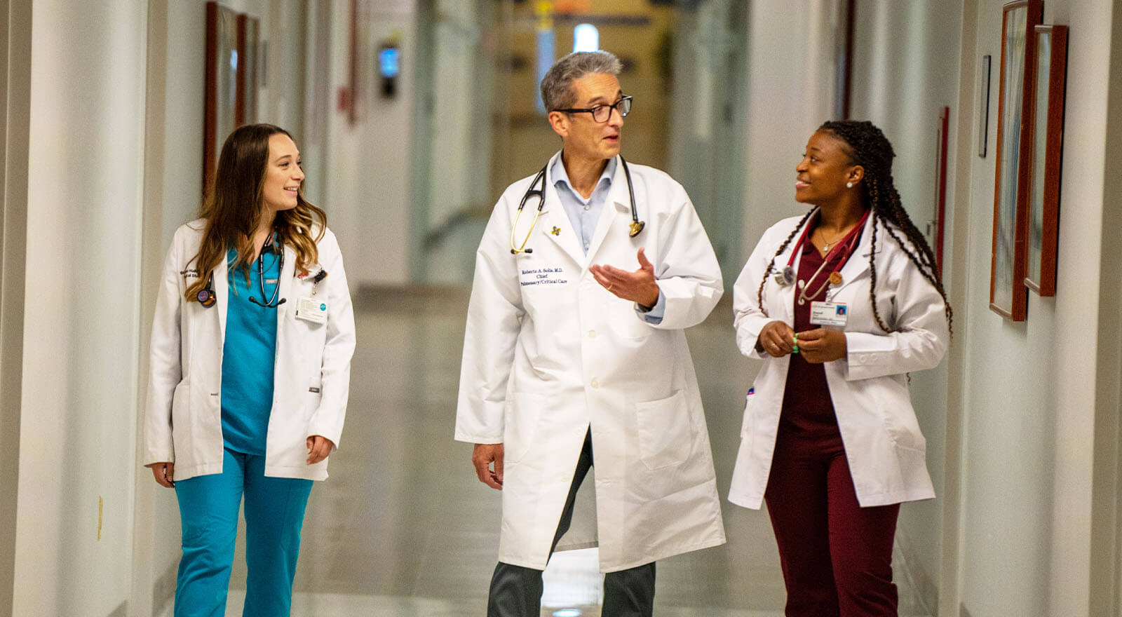 medical residents speaking with physician in hallway