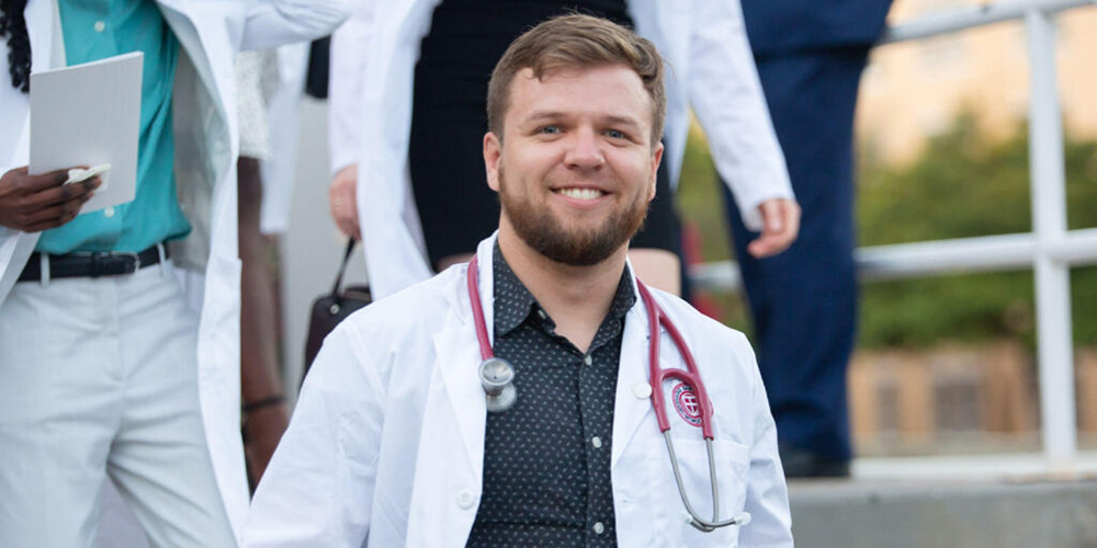 SGU student smiles wearing white coat