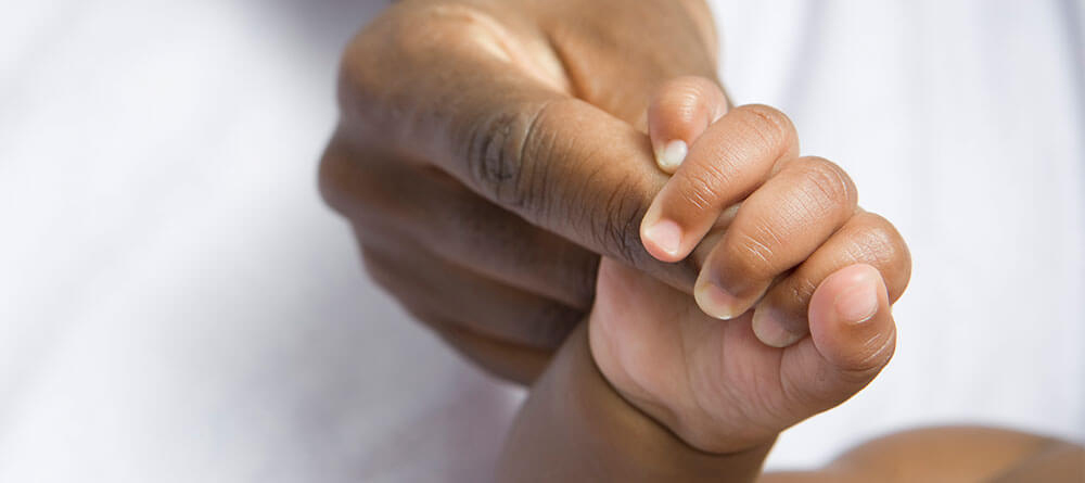 A close-up of a tiny baby's hand gently grasping an adult's hand, symbolizing love and connection.