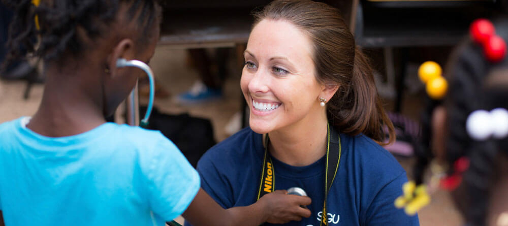 A small group of SGU students volunteer their time conducting physical exams during an outdoor clinic.|Skip the Med School Waitlist. Episode 1: 4 Perks of attending an international medical school.