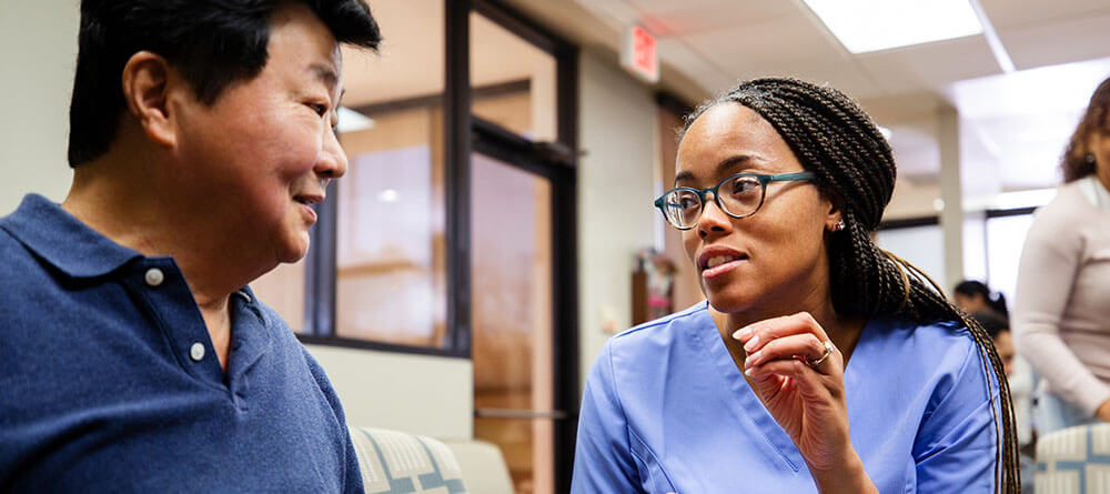 A doctor speaks with a patience in a clinic waiting room.