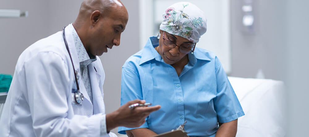 Hematologist oncologist speaks with cancer patient in exam room