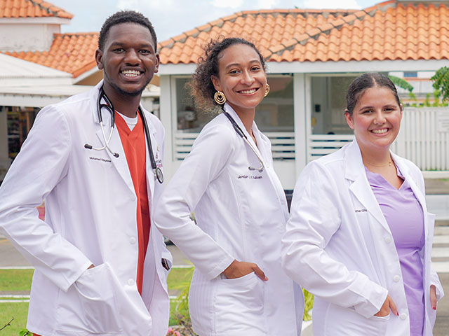 Three students in white coats on campus
