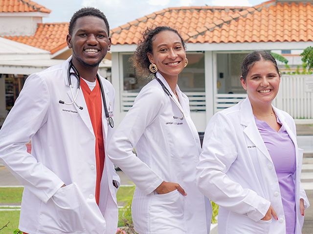 Three students in white coats on campus